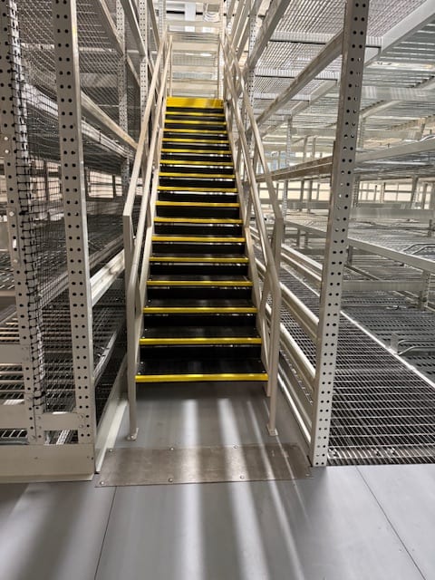 Fixed stair tower with striped treads providing access to upper levels of archive rack